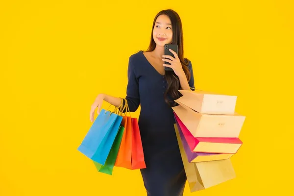 肖像画美しい若いアジアの女性でショッピングバッグクレジットカードとスマートフォン黄色隔離された背景 — ストック写真