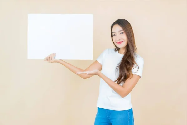 美丽的亚洲年轻女子在奶油背景上展示空白的白色广告牌纸片 — 图库照片