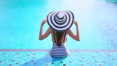 Otelde yüzme havuzunda dinlenen Asyalı güzel bir kadının görüntüsü.