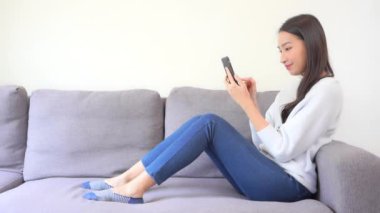 Evde akıllı telefon kullanan Asyalı kadının görüntüleri.