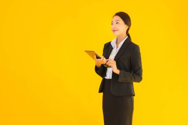 Güzel, genç Asyalı bir kadının portresi mutlu bir gülümseme ve sarı izole edilmiş arka planda akıllı tabletler.