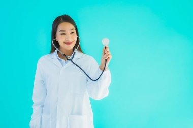 Klinikte ya da mavi izole edilmiş arka planda hastanede kullanmak üzere steteskoplu güzel Asyalı genç doktor kadın portresi.