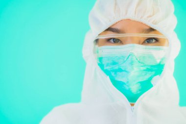 Güzel, genç Asyalı doktor kadın koronavirüsten korunmak için ppe ya da kişisel koruyucu ekipman takıyor ya da mavi izole arka planda beyaz kartı olan 19. bölgede yaşıyor.