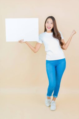 Güzel bir Asyalı kadın portresi. Krem arka planda boş beyaz ilan panosu kağıdı gösteriyor.
