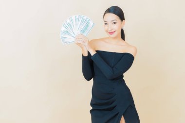 Asyalı güzel bir kadının portresi. Renkli arka planda bol para ve parayla gülümsüyor.