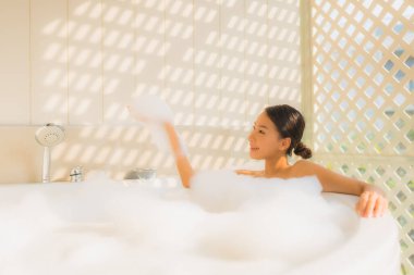 Portre genç Asyalı kadın rahatla spa konsepti için küvette banyo yap.