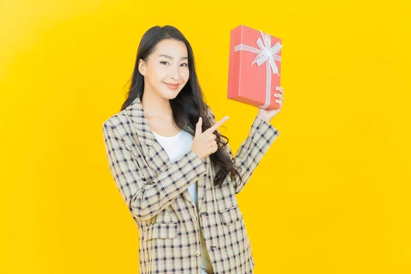 色彩艳丽的年轻亚洲女人带着红色礼品盒微笑 — 图库照片