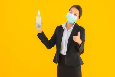 Güzel bir iş kadını portresi. Maske takıyor. Korunmak için alkol jeli kullanıyor.