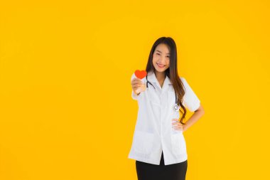 Güzel bir portre genç Asyalı doktor kadın, sarı izole edilmiş arka planda aşkın sembolü için kalbini göster.