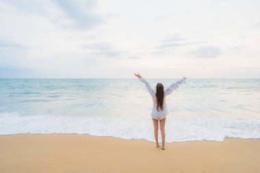 Güzel bir Asyalı kadın portresi deniz kenarında tatil yaparken rahatlar.