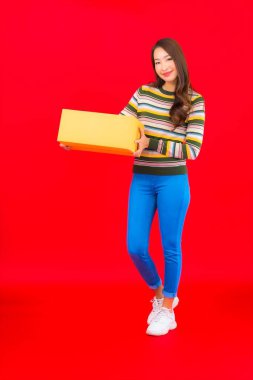 Güzel bir Asyalı kadının portresi. Kırmızı izole edilmiş arka planda bir paket kutusu var.