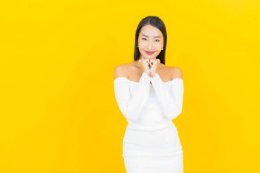 Portre güzel genç iş kadını gülümseyen ve eylem sarı arka planlı Asyalı kadın