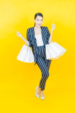 Portre güzel Asyalı kadın tebessümü ile renk arka planında alışveriş torbası