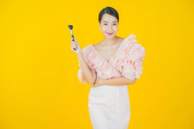 Renk arka planında makyaj fırçası olan güzel Asyalı kadın portresi.