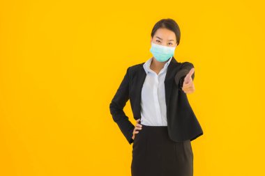 Güzel genç iş kadını portresi Korunmak için maske takıyor 19 koronavirüs sarı izole arka planda