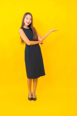 Güzel Asyalı iş kadını portresi. Sarı arka planda hareketli bir gülümseme.