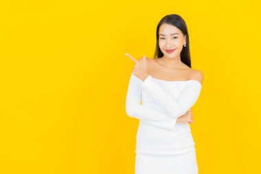 Portre güzel genç iş kadını gülümseyen ve eylem sarı arka planlı Asyalı kadın