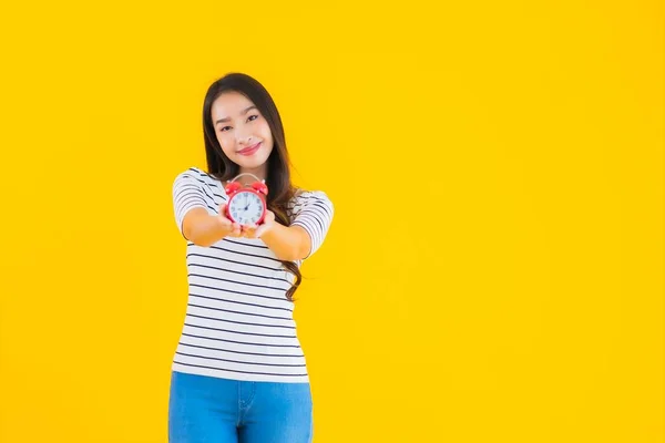 肖像美しい若いアジアの女性ショークロックまたはアラーム上の黄色隔離された背景 — ストック写真