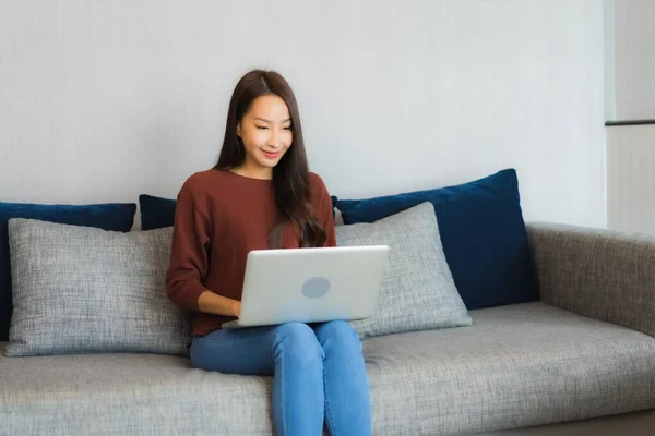 漂亮的年轻亚洲女人在客厅的沙发上使用电脑笔记本电脑 — 图库照片