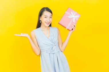 Güzel bir Asyalı kadının portresi. Arka planda kırmızı hediye kutusuyla gülümsüyor.