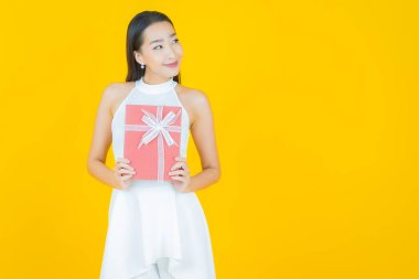 Güzel bir Asyalı kadının portresi. Arka planda kırmızı hediye kutusuyla gülümsüyor.