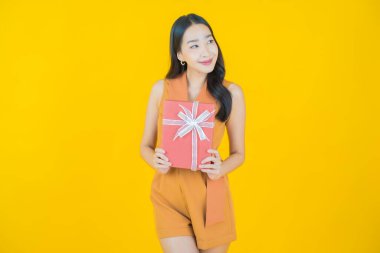 Güzel bir Asyalı kadının portresi. Arka planda kırmızı hediye kutusuyla gülümsüyor.