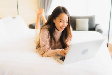 Yatak odasının iç kısmında dizüstü bilgisayar kullanan güzel Asyalı kadın portresi.