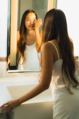 Güzel bir Asyalı kadın portresi makyaj malzemesi makyaj malzemesi ve yüz makyajı ile banyo içinde yüz maskesi.