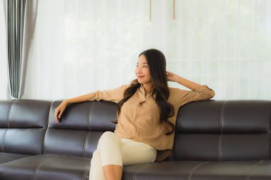 Güzel bir Asyalı kadın portresi. Mutlu bir gülümseme. Oturma odasındaki kanepede rahatla.