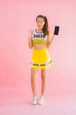 Pembe izole edilmiş arka planda akıllı cep telefonlu güzel Asyalı amigo kız portresi.