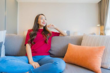 Güzel bir Asyalı kadın portresi. Yatak odasındaki kanepede rahatla. Gülümse.