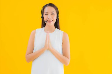 Güzel genç Asyalı kadın portresi, sarı izole arka planda yardım için çağrı merkezi.