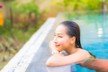 Güzel bir Asyalı kadının portresi tatil için yüzme havuzunda rahatlıyor.