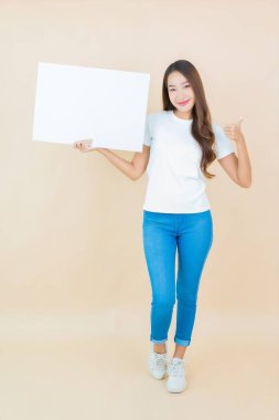 Güzel bir Asyalı kadın portresi. Krem arka planda boş beyaz ilan panosu kağıdı gösteriyor.