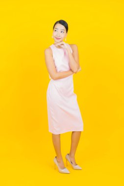 Asyalı güzel bir kadının portresi. Sarı arka planda hareketli gülümsüyor.