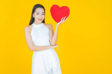 Portre güzel Asyalı genç kadın gülümsüyor kalp yastığı şeklinde renk arkaplan