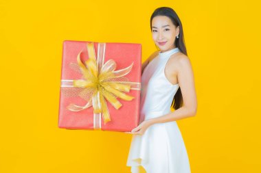 Güzel bir Asyalı kadının portresi. Arka planda kırmızı hediye kutusuyla gülümsüyor.