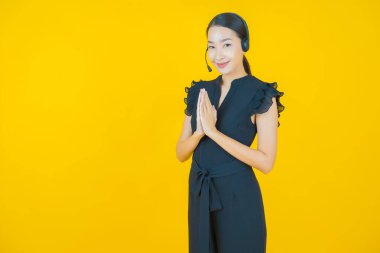 Sarı arka planda çağrı merkezi müşteri hizmetleri merkezi olan güzel Asyalı kadın portresi