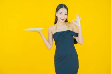 Güzel Asyalı bir kadının portresi. Arka planda boş tabak tabağıyla gülümsüyor.