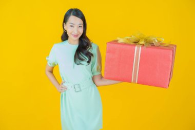 Güzel bir Asyalı kadının portresi. Arka planda kırmızı hediye kutusuyla gülümsüyor.