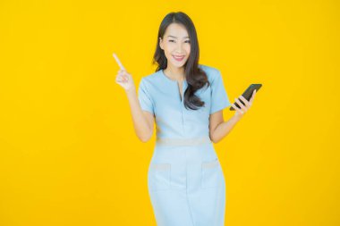 Renkli arka planda akıllı cep telefonuyla güzel Asyalı kadın gülümsemesi