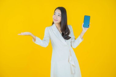 Renkli arka planda akıllı cep telefonuyla güzel Asyalı kadın gülümsemesi