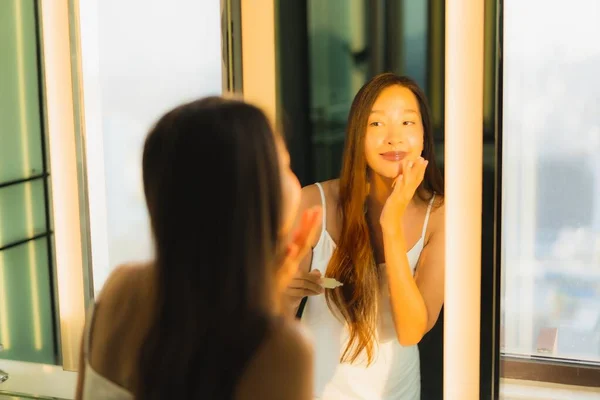 肖像美しい若いアジアの女性が適用されますクリームオン彼女の顔と顔でバスルームインテリア — ストック写真