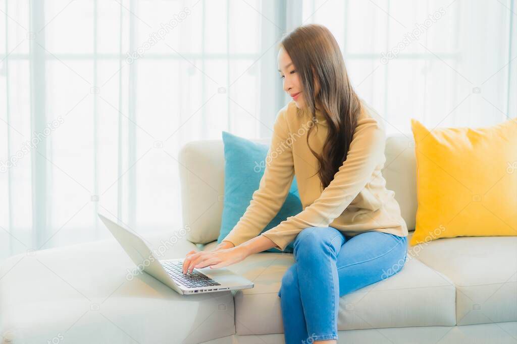 Portrait beautiful young asian woman use computer laptop on sofa decoration interior of living room