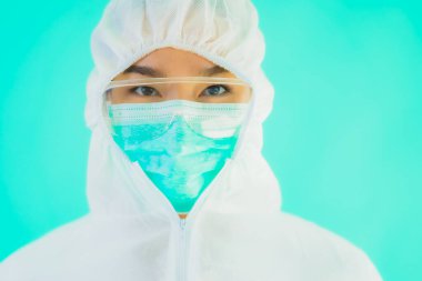 Güzel, genç Asyalı doktor kadın portre. Koronavirüsten ya da mavi arka planda kovid19 'dan korunmak için ppe ya da kişisel koruyucu ekipman takıyor.
