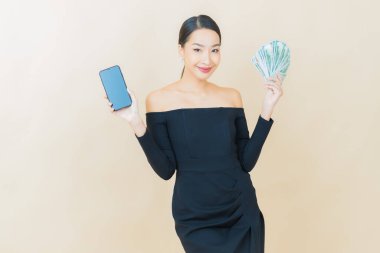 Asyalı güzel bir kadının portresi. Renkli arka planda bol para ve parayla gülümsüyor.