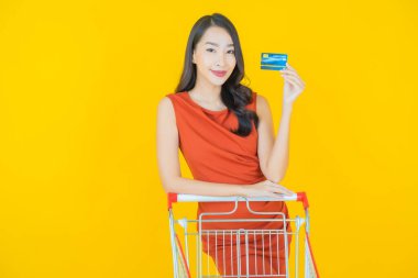 Renkli arka planda süpermarketten alınmış market sepetiyle gülümseyen güzel Asyalı kadın portresi.