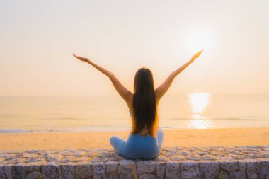 Genç Asyalı kadının portresi sağlık için gün doğumunda deniz kıyısı okyanusunda meditasyon yapıyor.