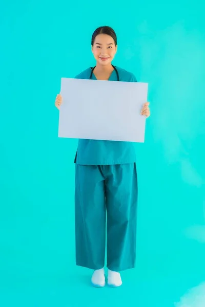 Portrait beautiful young asian doctor woman with empty paper board for copy space on blue isolated background - Healthcare in hospital and clinic concept