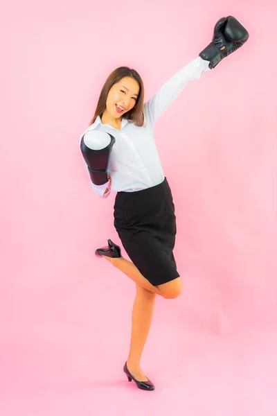 Portrait beautiful young asian woman with boxing glove ready to fight on pink background